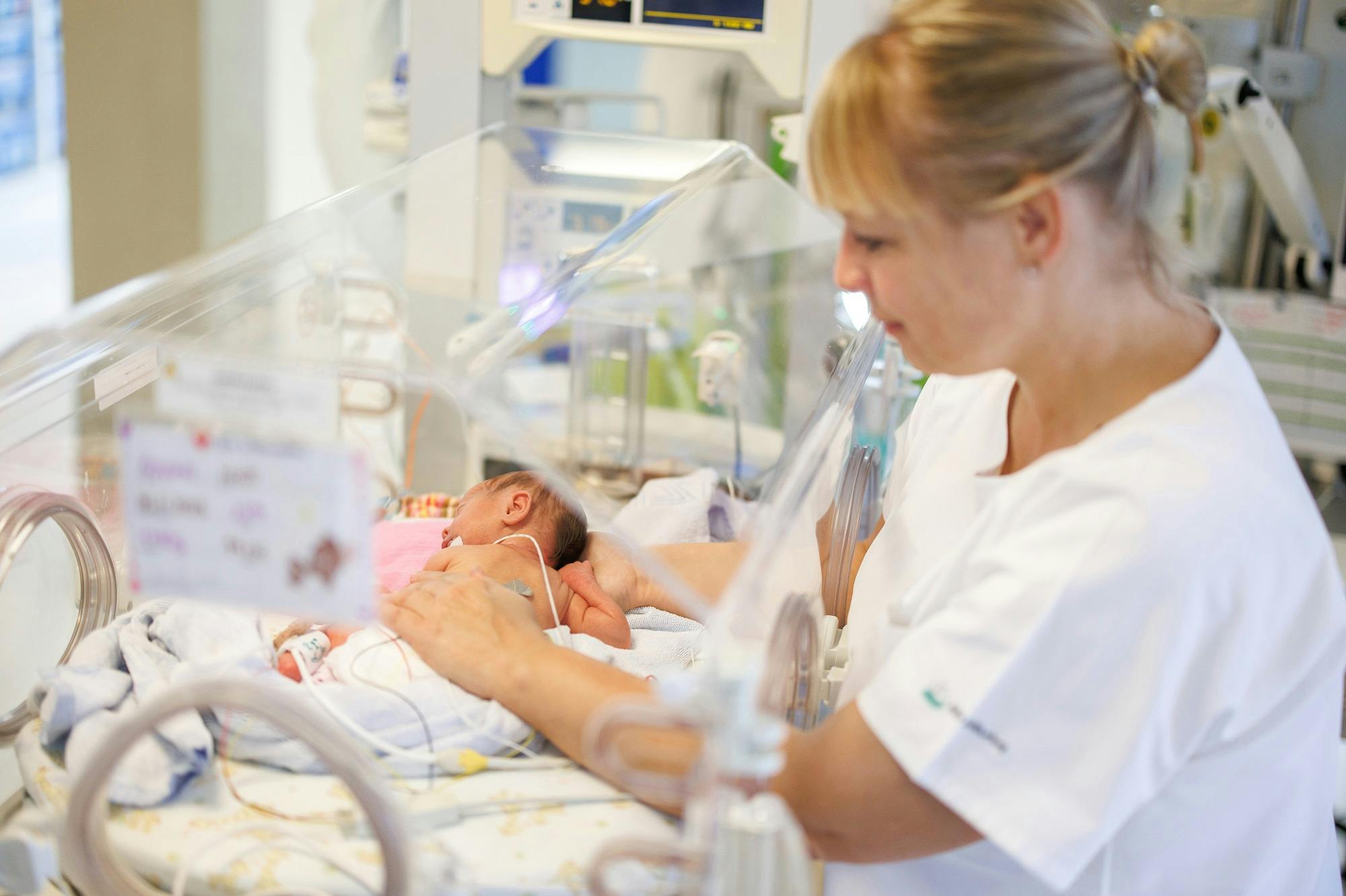 Nurse looks after a newborn baby in an incubator.