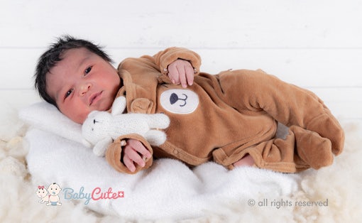 Säugling in einem Bärenkostüm hält ein Plüschtier.
