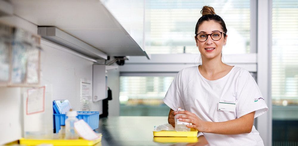 Smiling nurse with glasses stands in the hospital.