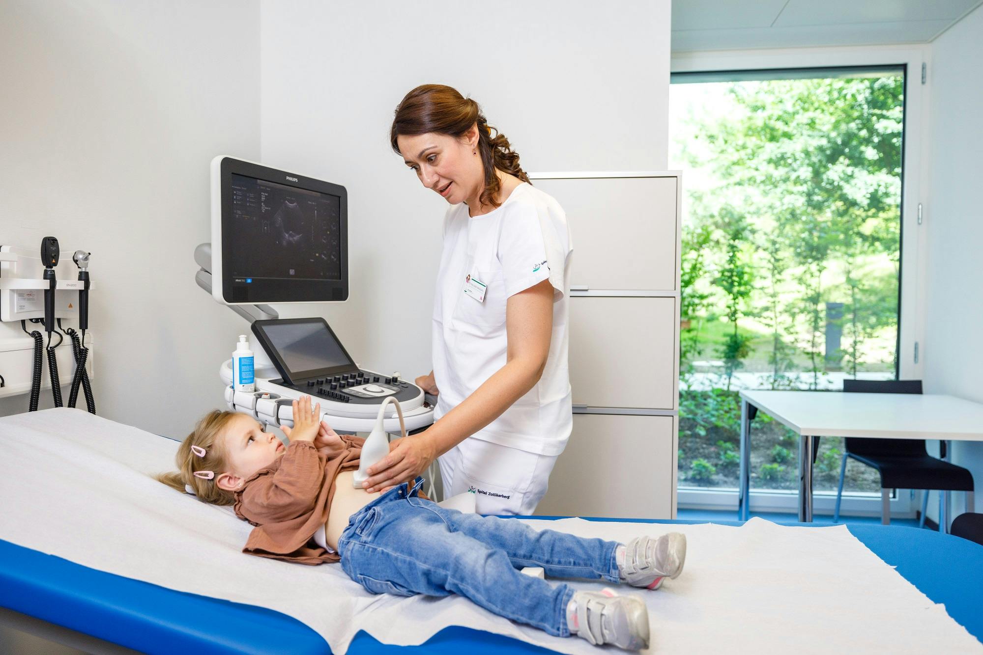 Ultraschalluntersuchung eines Kindes durch eine medizinische Fachkraft in einer Klinik.