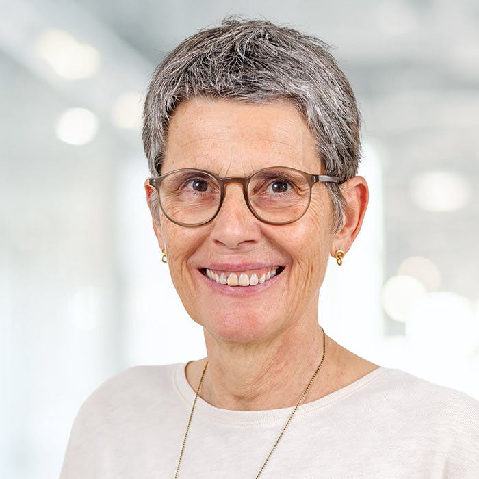 Portrait of a smiling older woman with short grey hair and glasses.