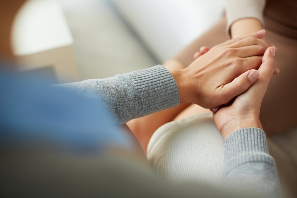 Two people hold hands for support and comfort.