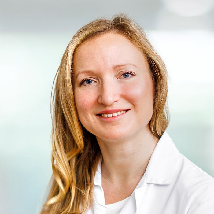 Smiling woman in a white coat against a blurred background for SEO and accessibility.