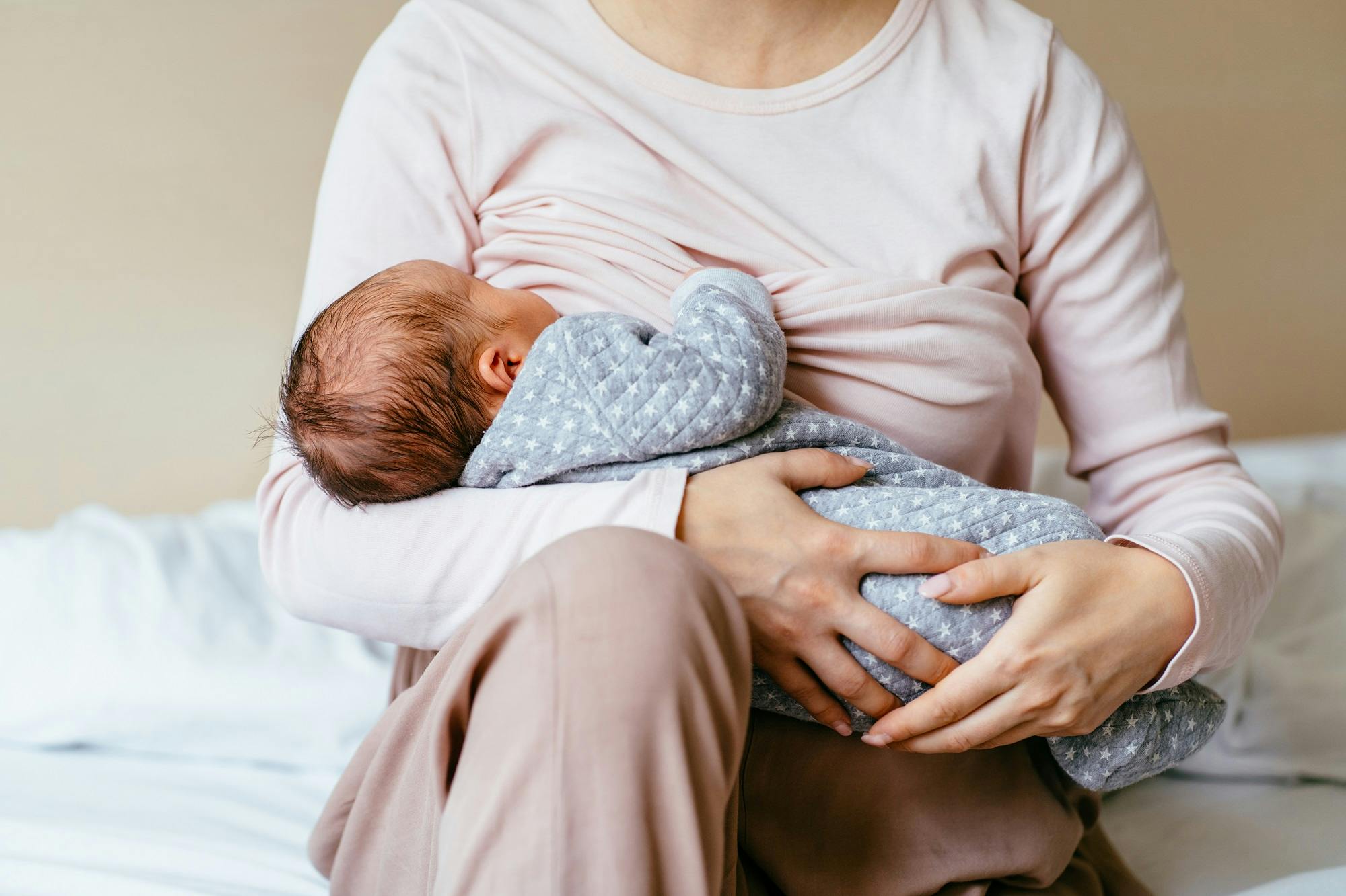 Mutter hält schlafendes Neugeborenes im Arm.
