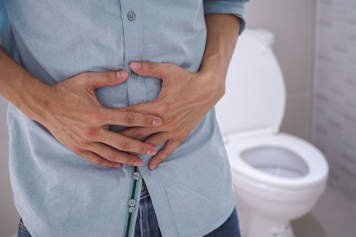 Person mit Bauchschmerzen vor einer Toilette