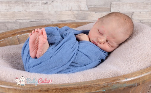 Schlafendes Neugeborenes in blauer Decke gewickelt.