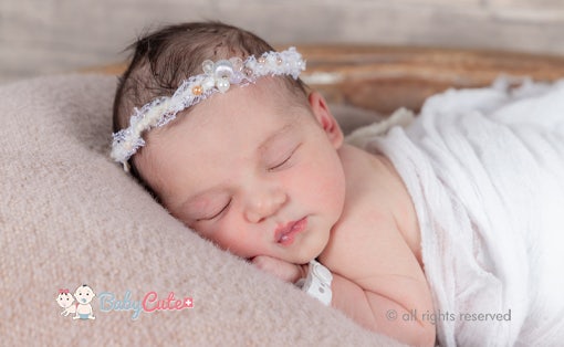Neugeborenes mit Stirnband schläft friedlich.