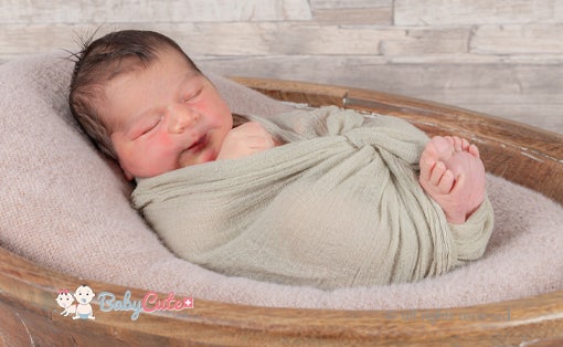 Neugeborenes eingewickelt in eine Decke, schläft in einem Korb.