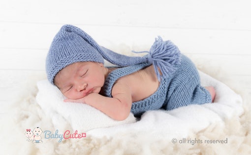 Newborn baby sleeping in blue knitted clothes with cap.