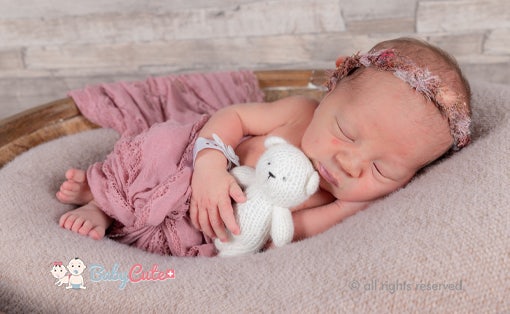 Schlafendes Neugeborenes mit Kuscheltier und Stirnband