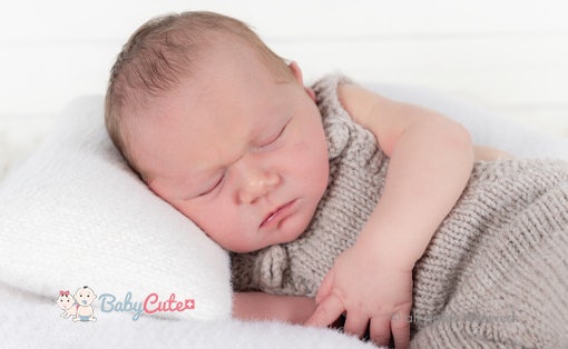 Schlafendes Neugeborenes in gestricktem Outfit.