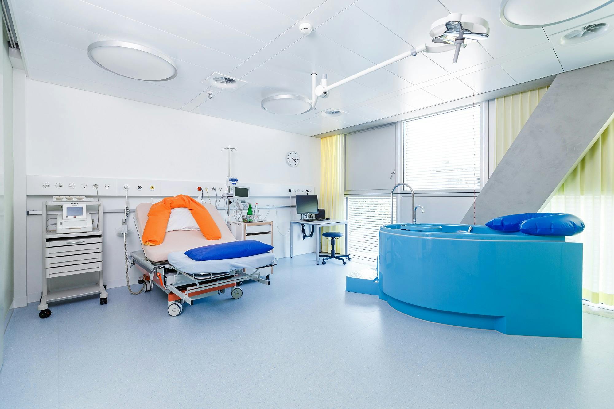 Krankenhaus-Geburtszimmer mit Entbindungsbett und Geburtsbadewanne.