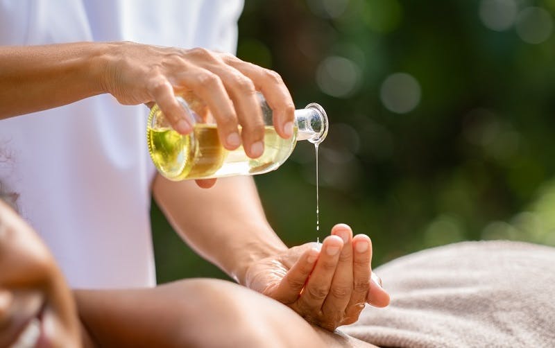 Person gießt Öl in die Handfläche für eine Massage oder Hautpflege.