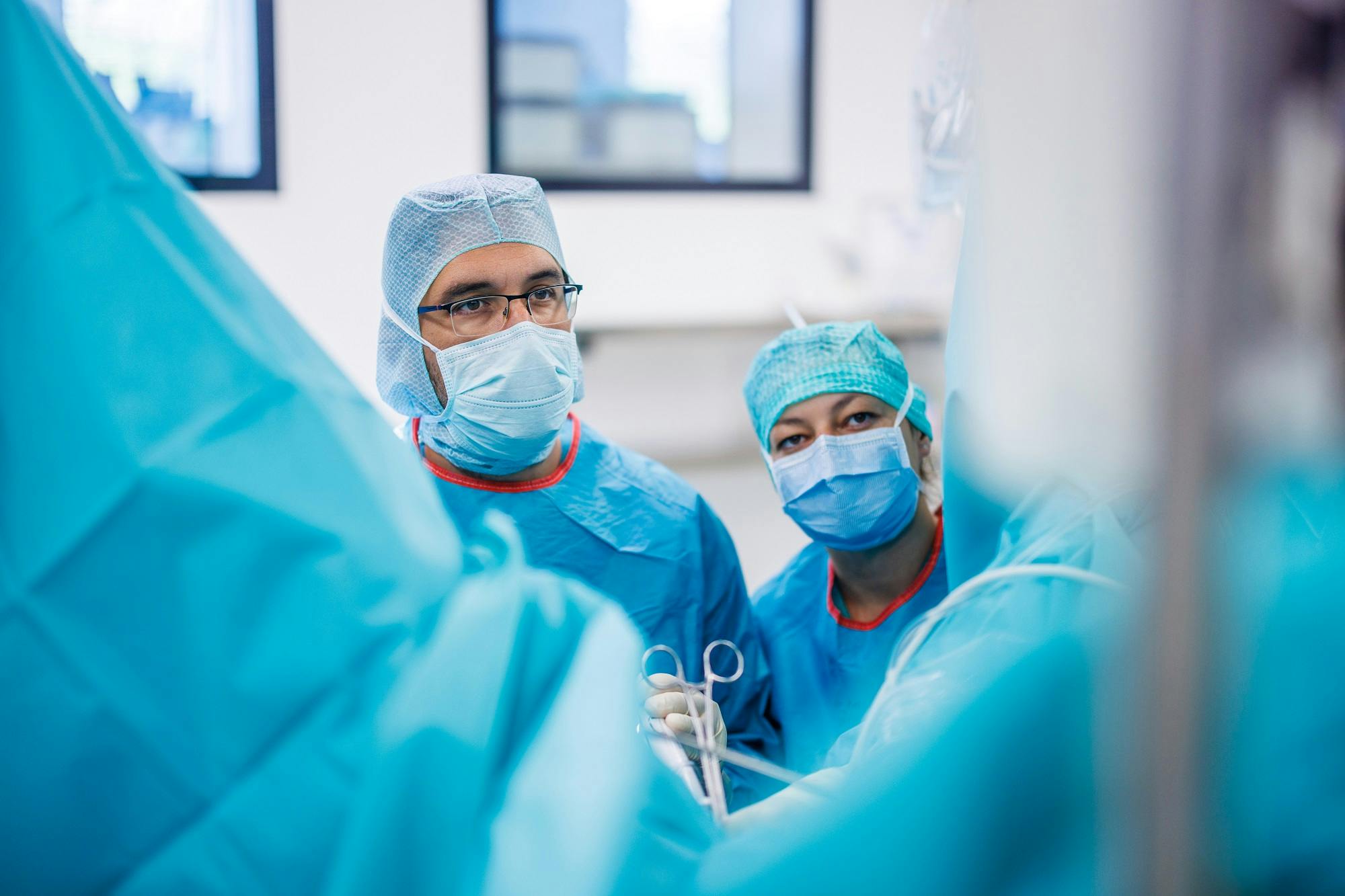 Chirurgen im OP-Saal mit medizinischer Ausrüstung und Schutzkleidung.