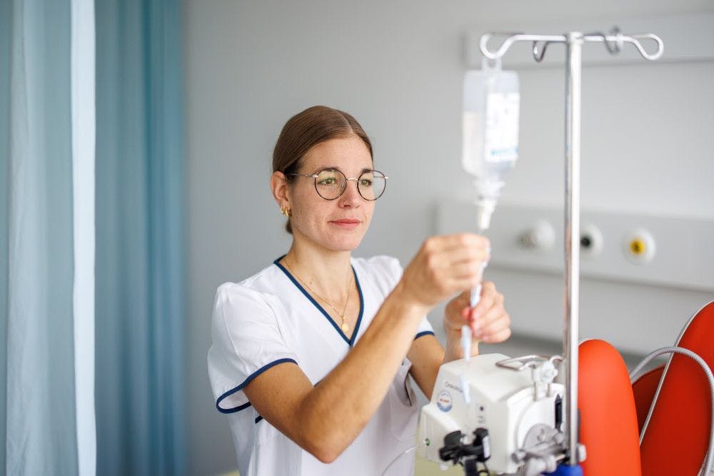 Nurse sets up infusion in hospital room.