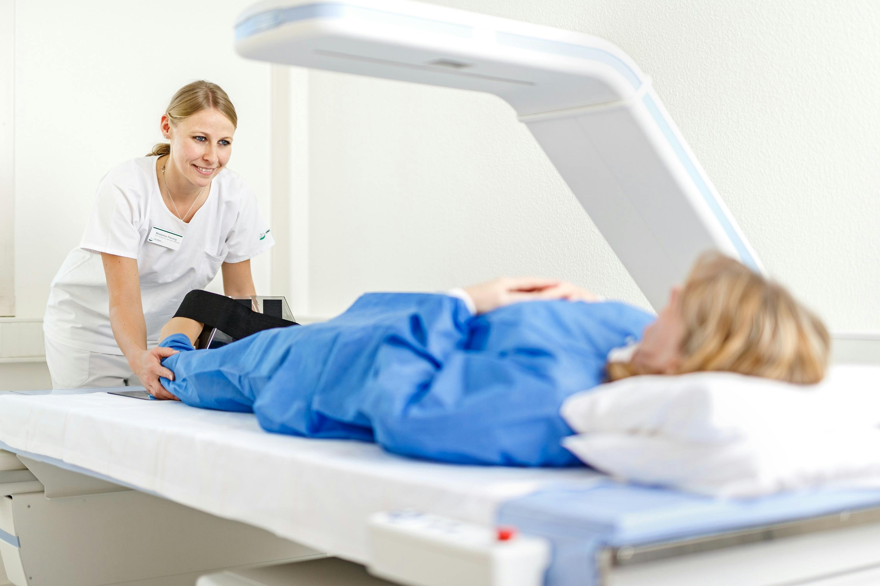 Medizinische Fachkraft bedient MRT-Gerät während Patientin untersucht wird.