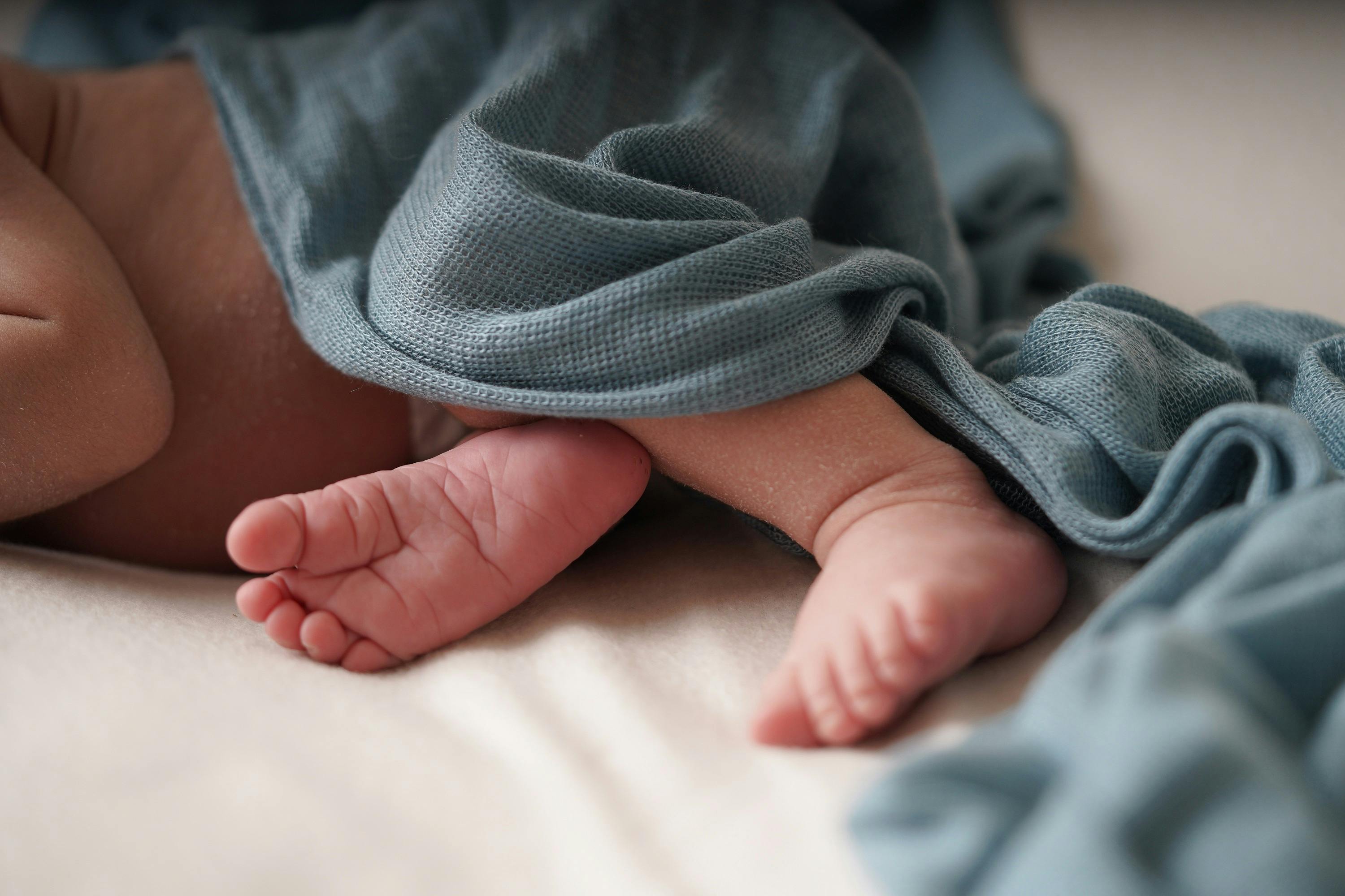 Baby feet under a blue blanket.