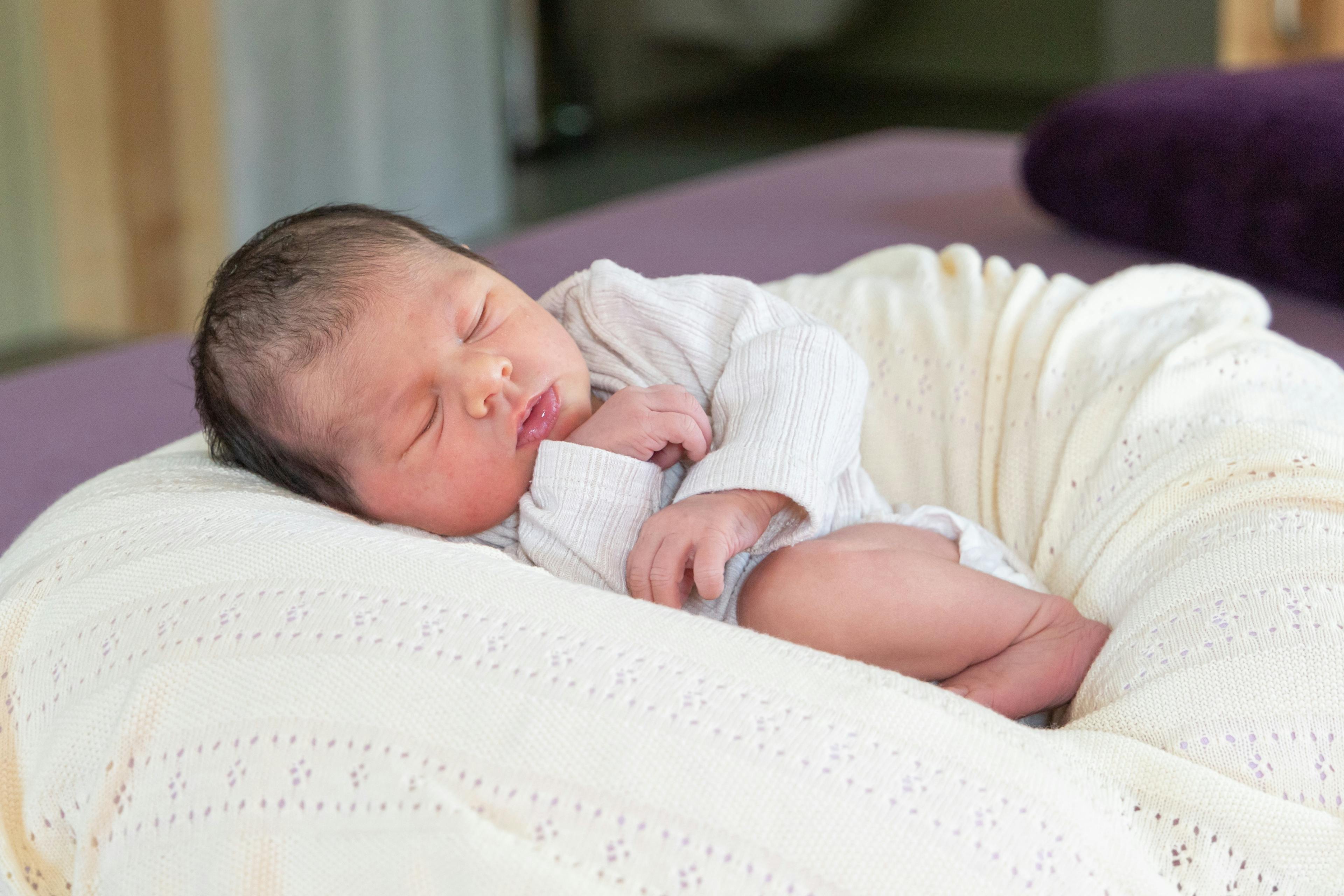 Sleeping newborn baby on a white blanket.