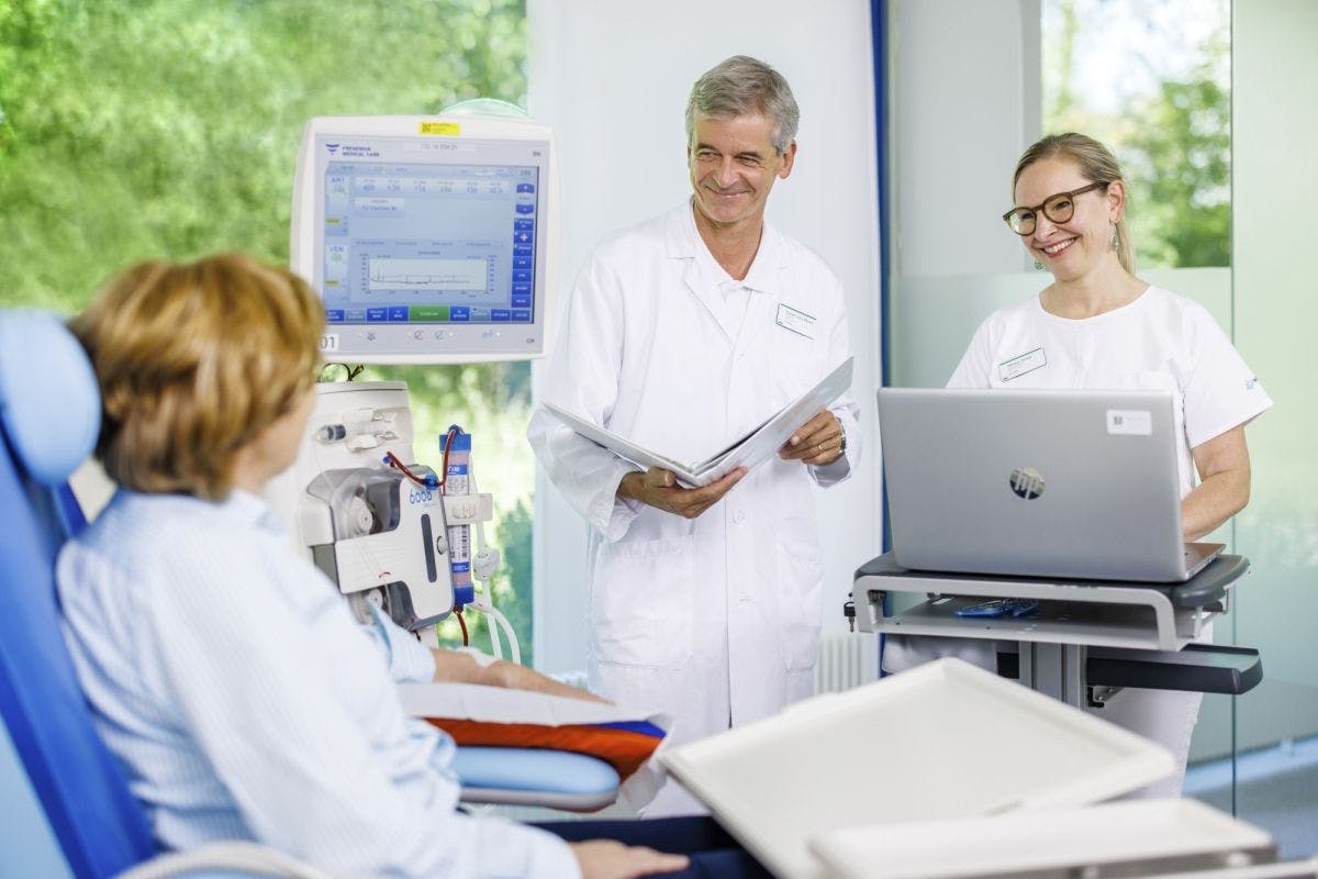 Lächelndes medizinisches Personal mit Unterlagen und Laptop in einer hellen Klinikumgebung.