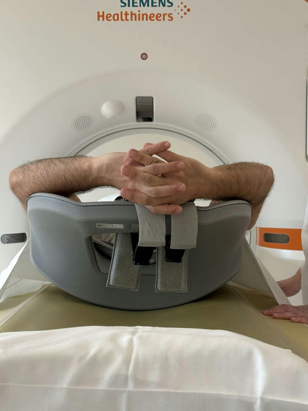 Patient in an MRI scanner with clasped hands.