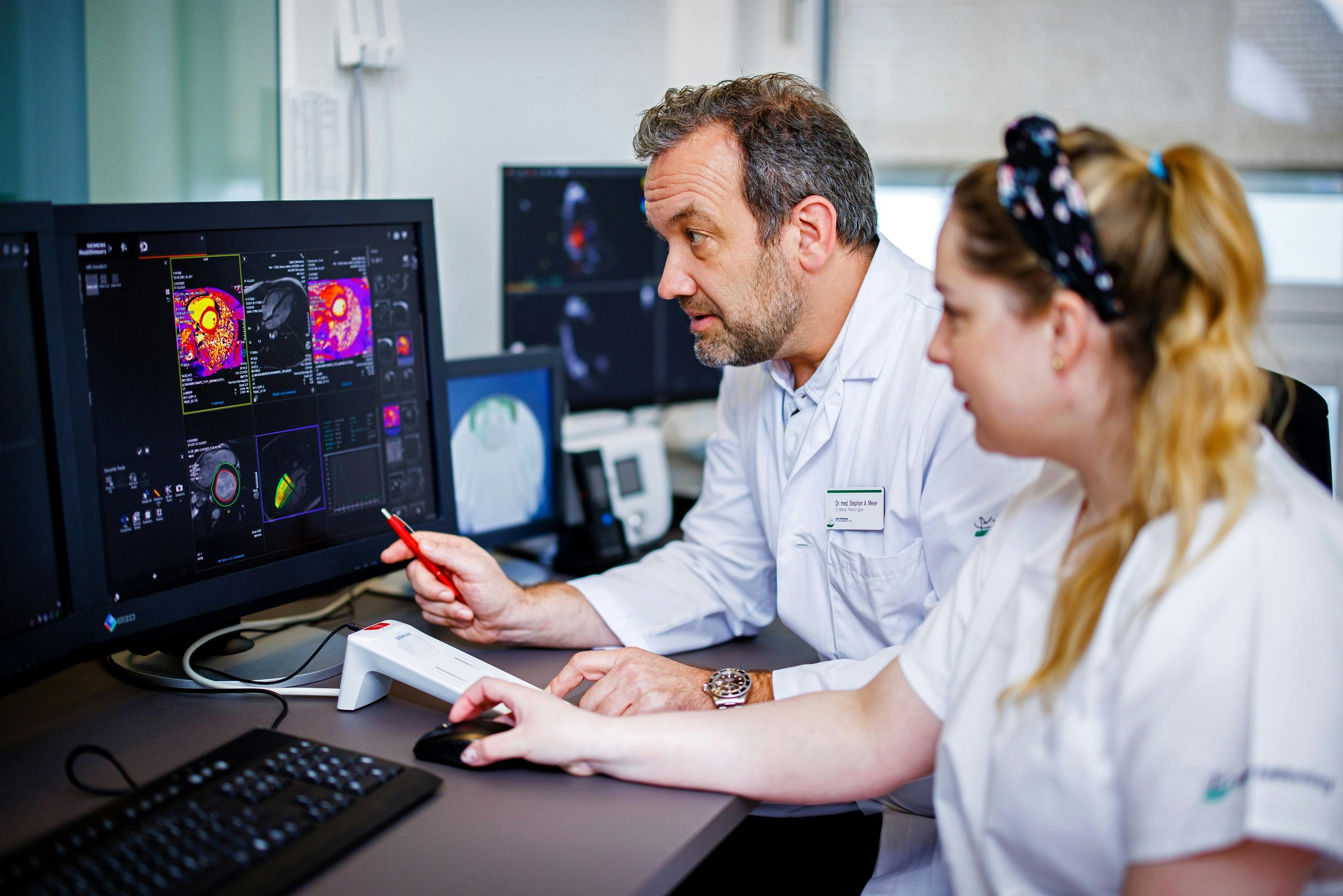 Two doctors analyse cardiac imaging data on computer screens.